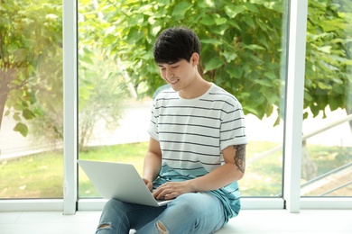 Photo of Man in casual clothes with laptop near window indoors