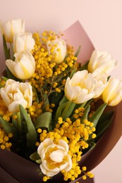 Photo of Bouquet of beautiful spring flowers near beige wall, closeup