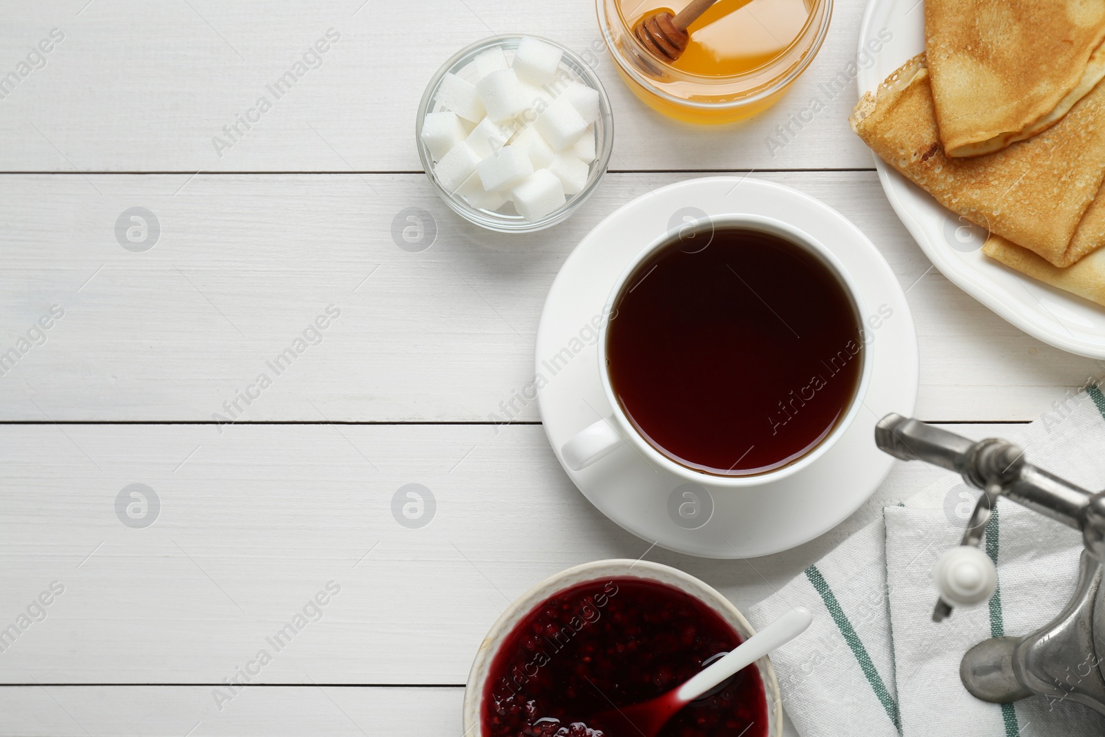 Photo of Metal samovar with cup of tea and treats on white wooden table, flat lay. Space for text