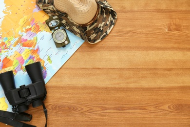 Photo of Flat lay composition with map and camping equipment on wooden background. Space for text