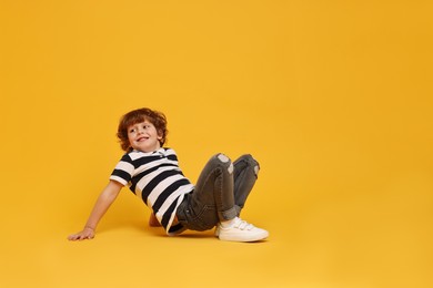 Happy little boy dancing on yellow background