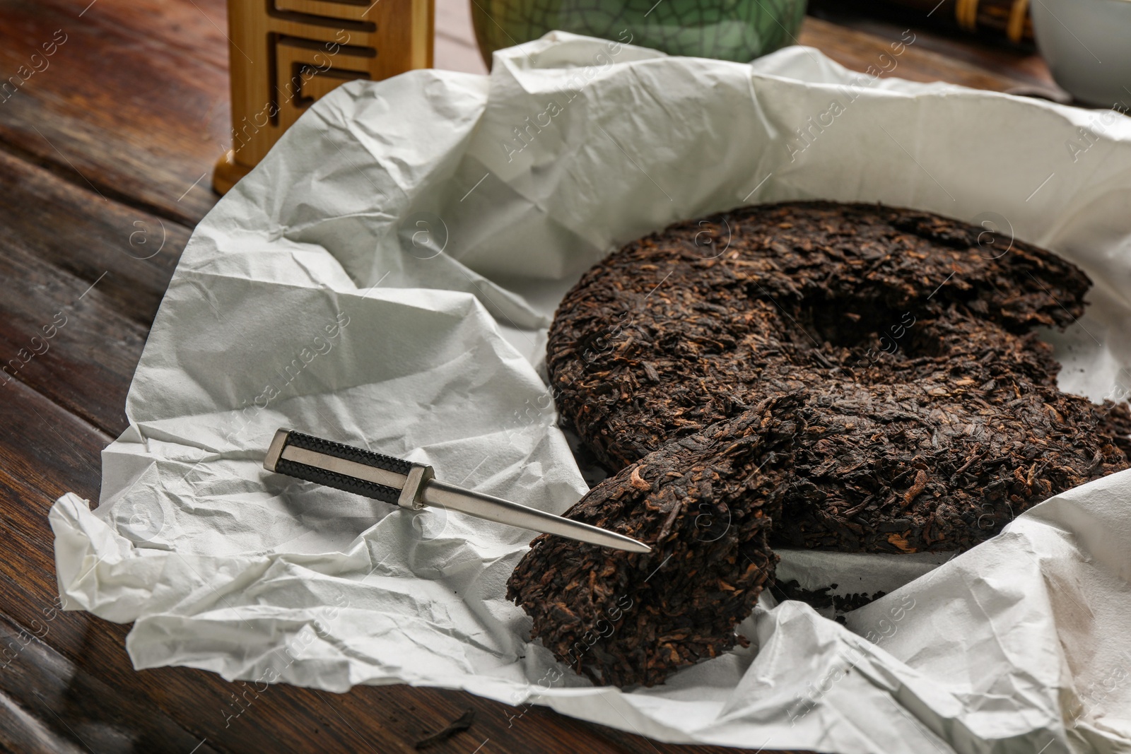 Photo of Broken disc shaped pu-erh tea and knife on wooden table