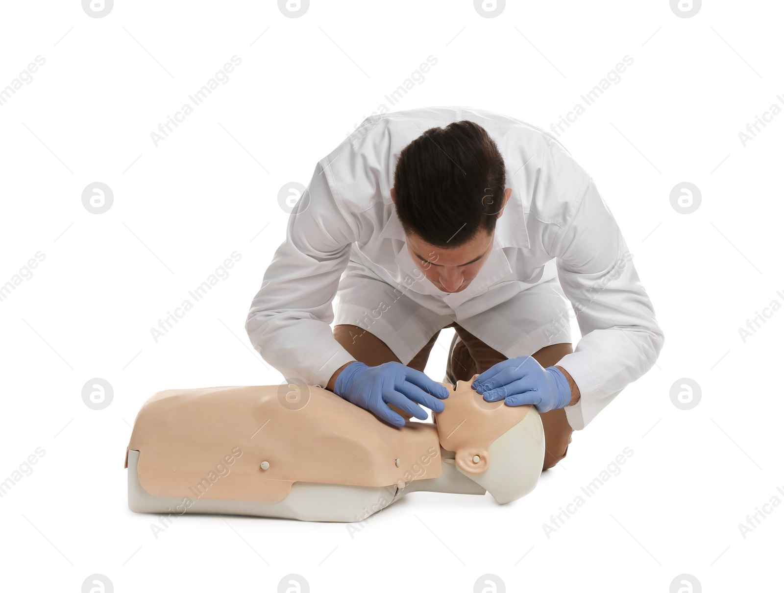 Photo of Doctor in uniform practicing first aid on mannequin against white background