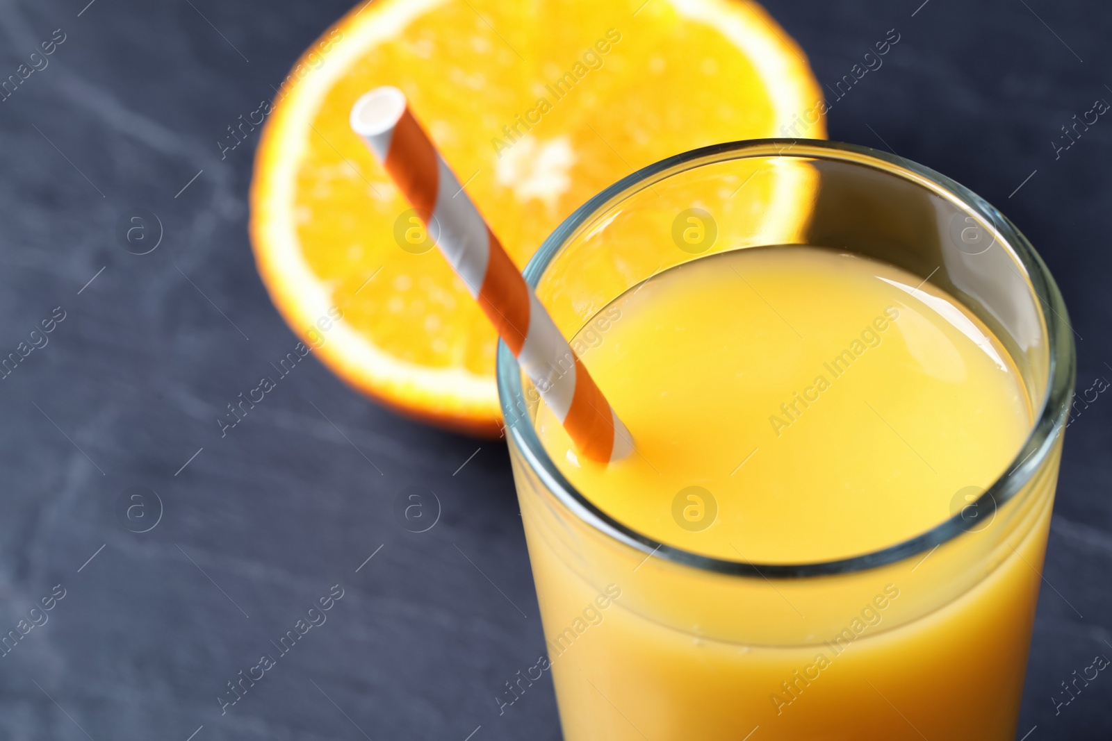 Photo of Glass of delicious fresh orange juice on dark table, closeup