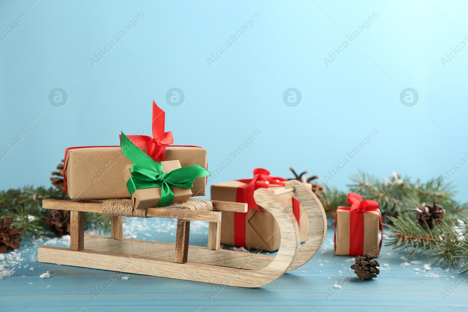 Photo of Beautiful Christmas composition with miniature sleigh on light blue table. Space for text