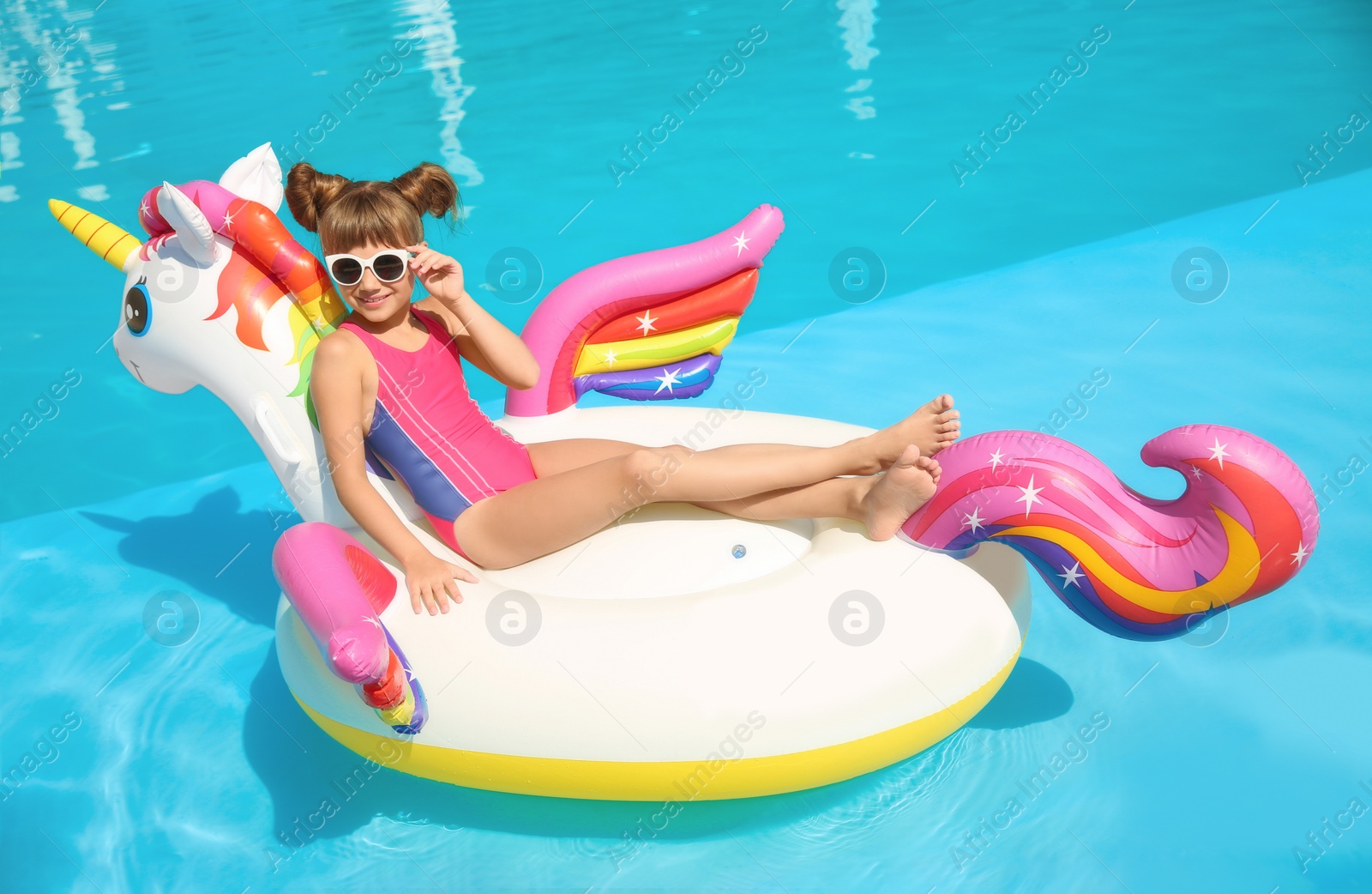 Photo of Little girl on inflatable mattress in swimming pool