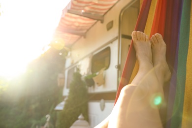 Photo of Young woman resting in hammock near motorhome outdoors on sunny day, closeup of legs