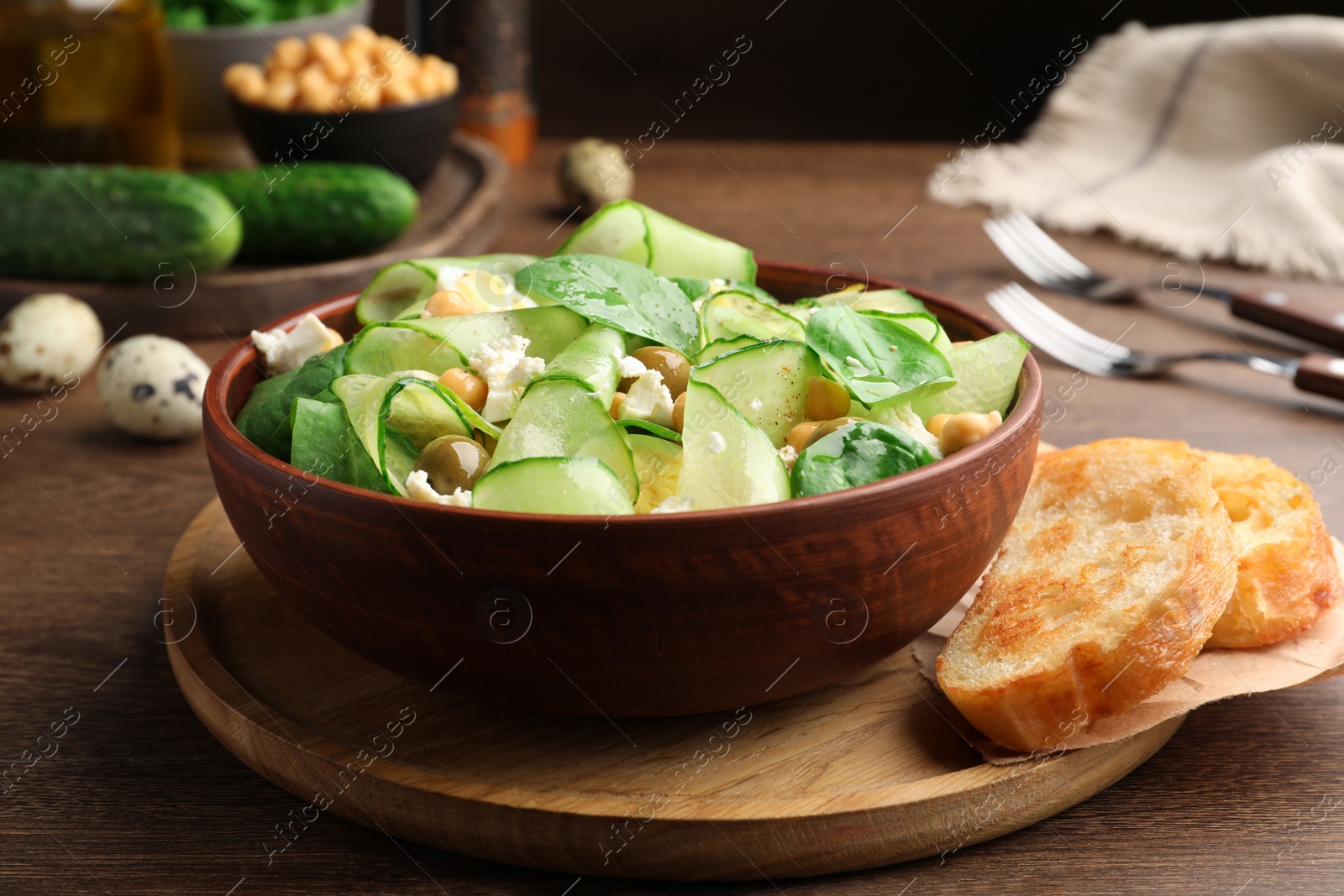 Photo of Delicious cucumber salad and toasted bread served on wooden table