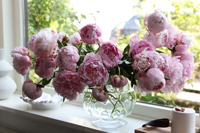 Photo of Beautiful pink peonies in vase on window sill. Interior design