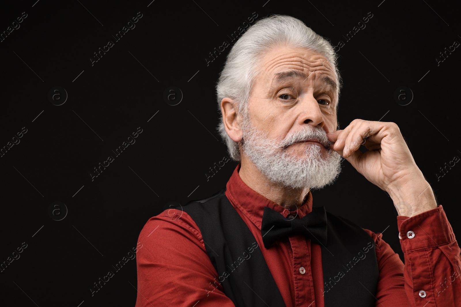 Photo of Senior man touching mustache on black background, space for text