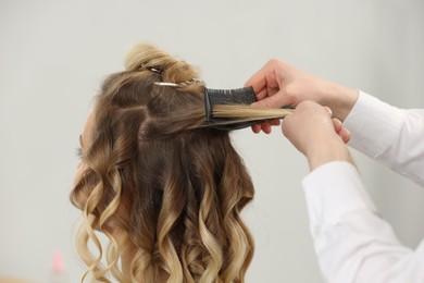 Hair styling. Professional hairdresser combing woman's hair in salon, closeup