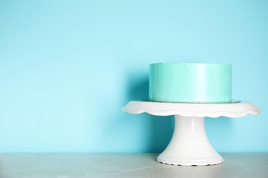 Photo of Fresh delicious birthday cake on stand against color background. Space for text