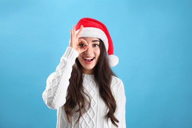 Photo of Beautiful woman wearing Santa Claus hat on light blue background