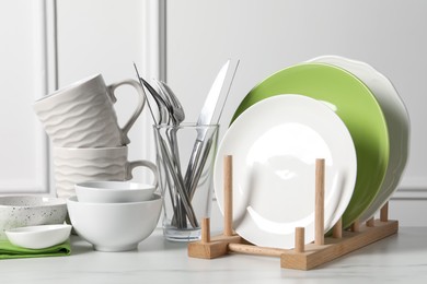 Photo of Beautiful ceramic dishware, cups and cutlery on white marble table