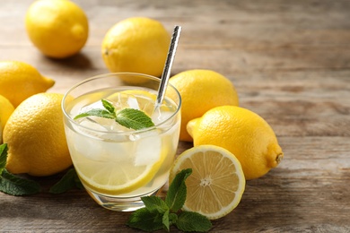 Photo of Natural lemonade with mint and fresh fruits on wooden table, closeup. Summer refreshing drink