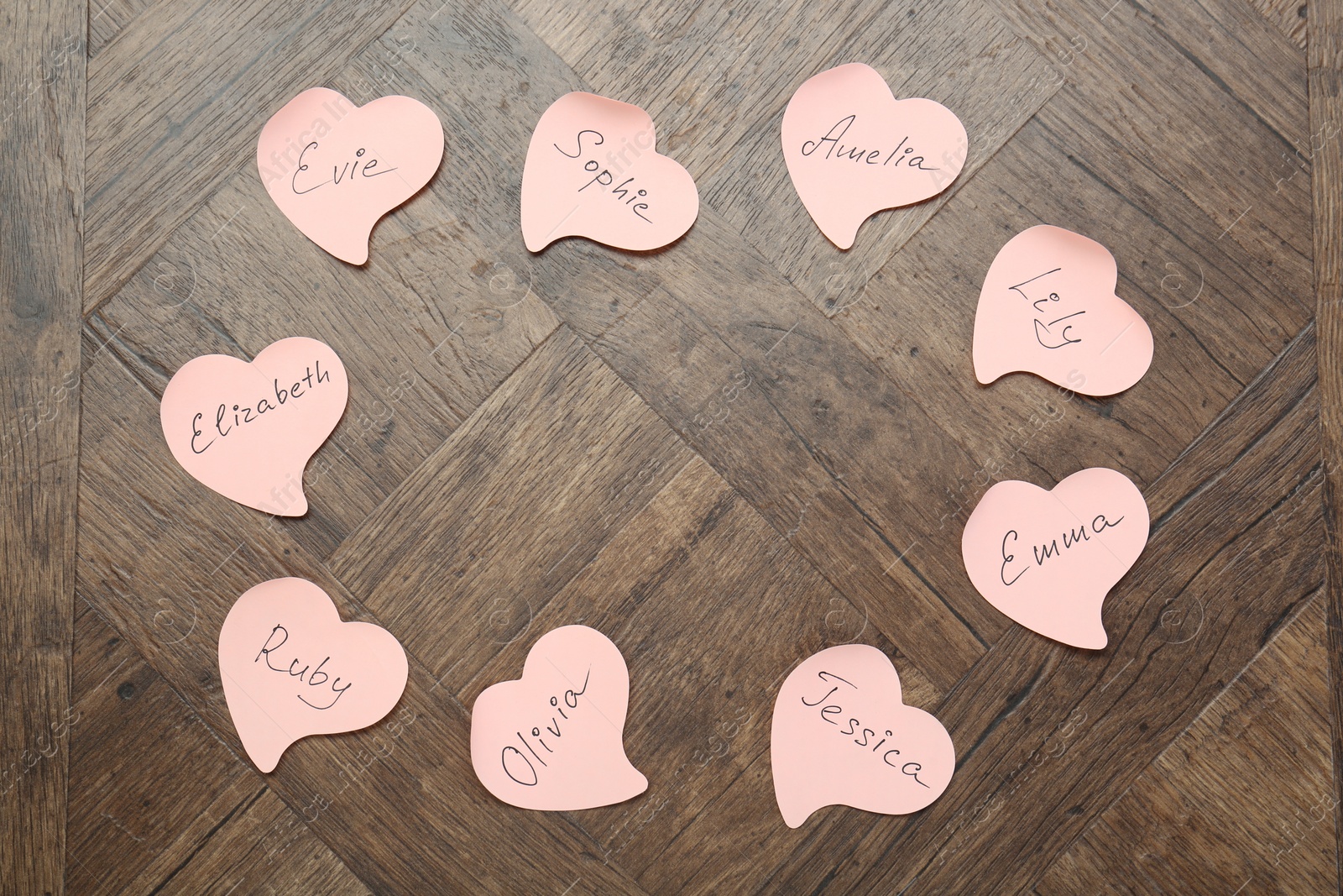 Photo of Choosing baby's name. Paper stickers with different names on wooden background, flat lay. Space for text