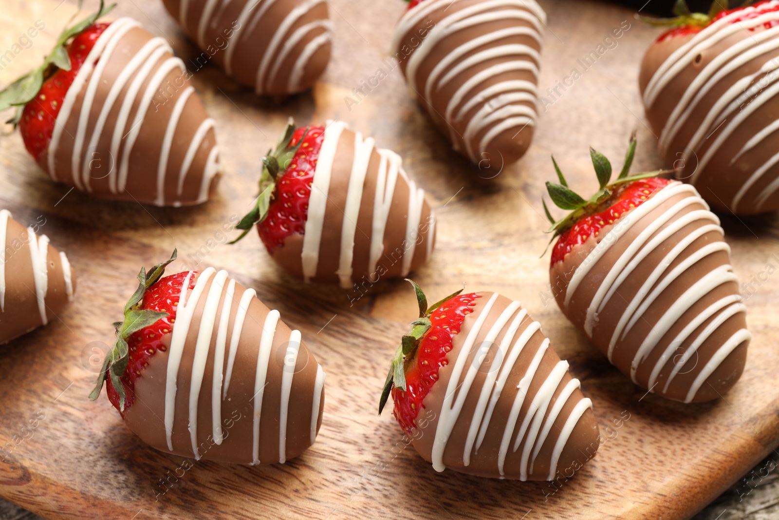 Photo of Delicious chocolate covered strawberries on wooden board, closeup