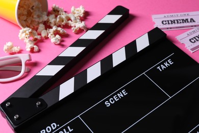 Photo of Clapperboard, 3D glasses, popcorn and movie tickets on pink background, closeup