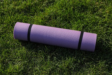 Photo of Bright exercise mat on fresh green grass outdoors