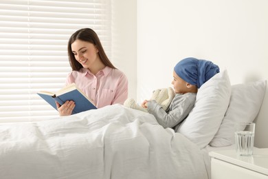Photo of Childhood cancer. Mother reading book to daughter in hospital