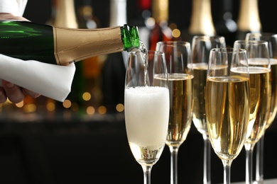 Photo of Pouring champagne into glasses on blurred background, closeup