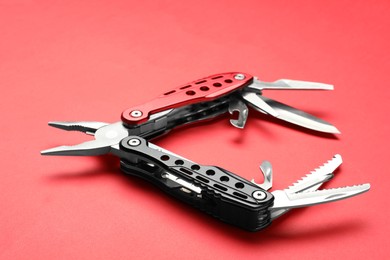 Photo of Compact portable multitool on red background, closeup