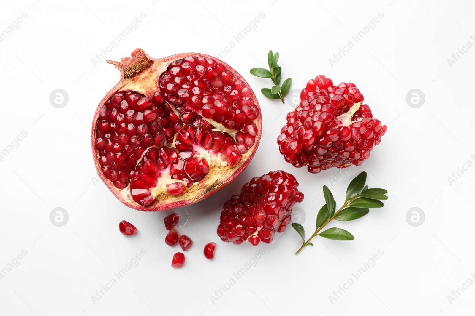 Photo of Cut fresh pomegranate and green leaves on white background, flat lay