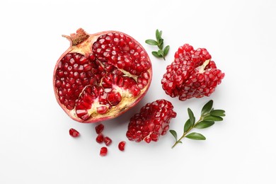 Photo of Cut fresh pomegranate and green leaves on white background, flat lay