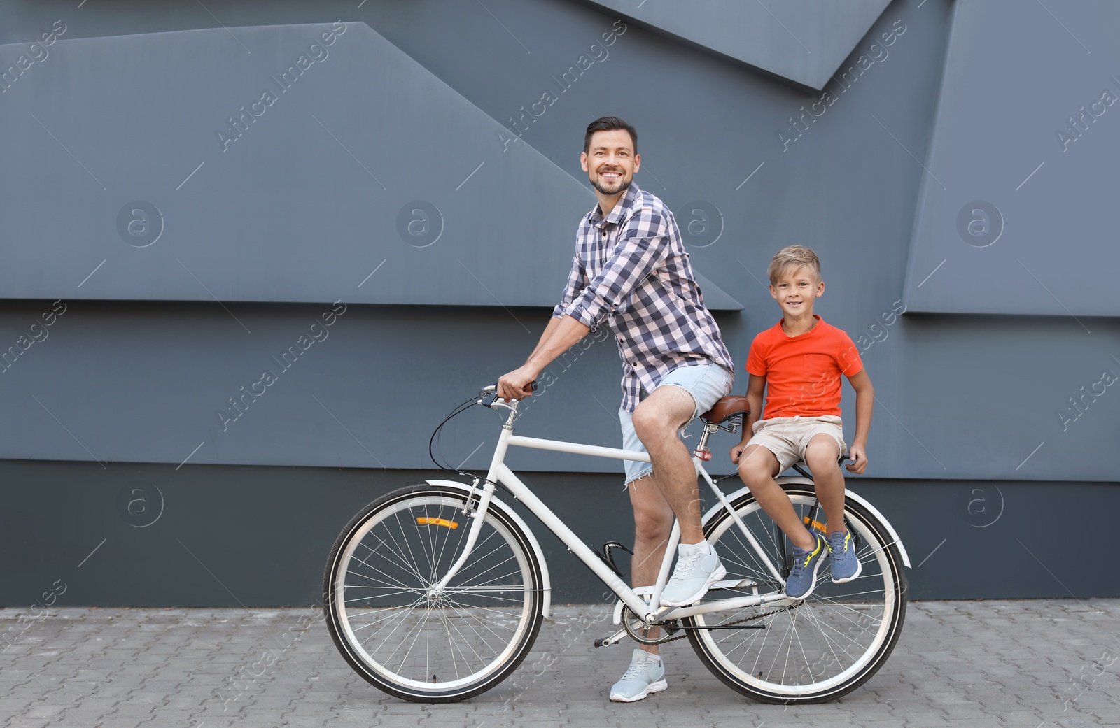 Photo of Father and son riding bicycle on street