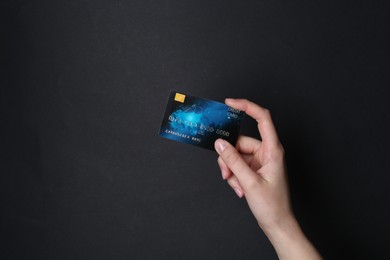 Photo of Woman holding credit card on black background, closeup