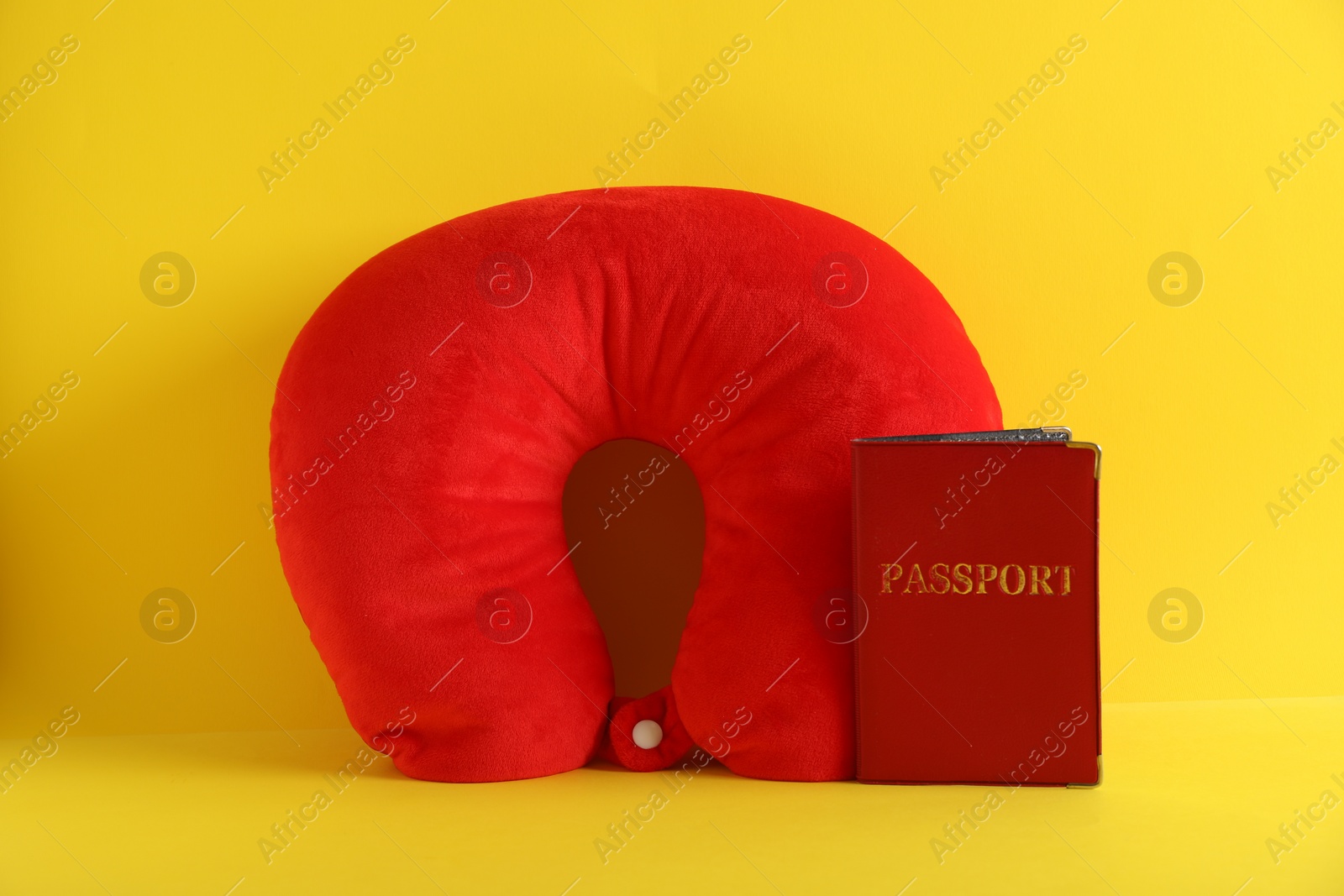 Photo of Red travel pillow and passport on yellow background