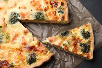Photo of Delicious homemade quiche with salmon and broccoli on parchment paper, top view