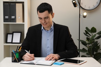 Photo of Man taking notes at table in office