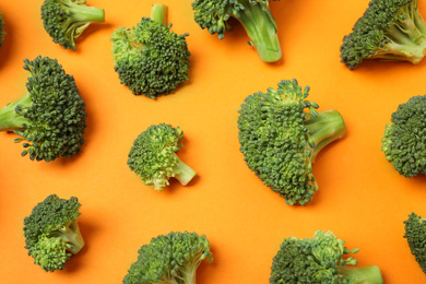 Photo of Fresh tasty broccoli on orange background, flat lay