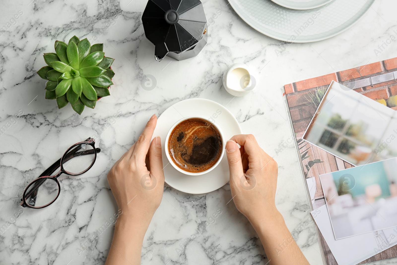 Photo of Young woman with cup of delicious hot coffee at table, top view