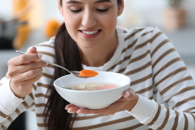 Photo of Young woman eating tasty vegetable soup indoors