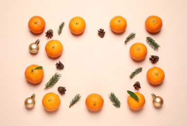 Photo of Frame made of Christmas balls and tangerines on beige background, flat lay. Space for text