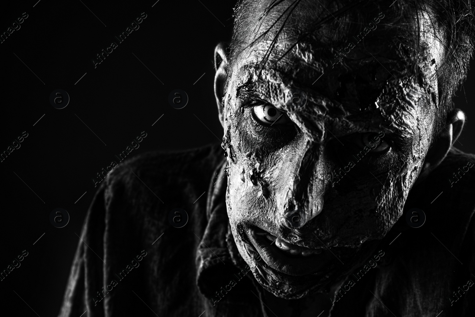 Photo of Scary zombie on dark background, black and white effect. Halloween monster