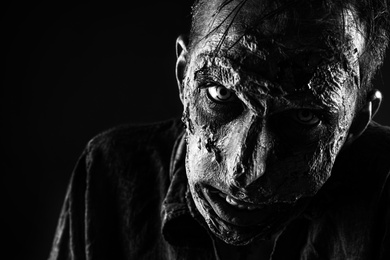 Photo of Scary zombie on dark background, black and white effect. Halloween monster