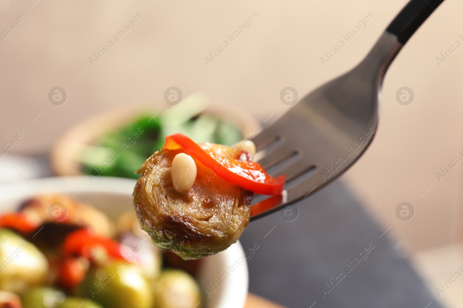 Photo of Fork with warm Brussels sprouts salad over table, closeup