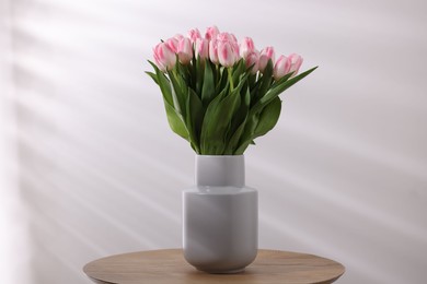 Beautiful bouquet of fresh pink tulips on table against light background