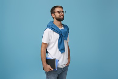 Photo of Student with books on light blue background