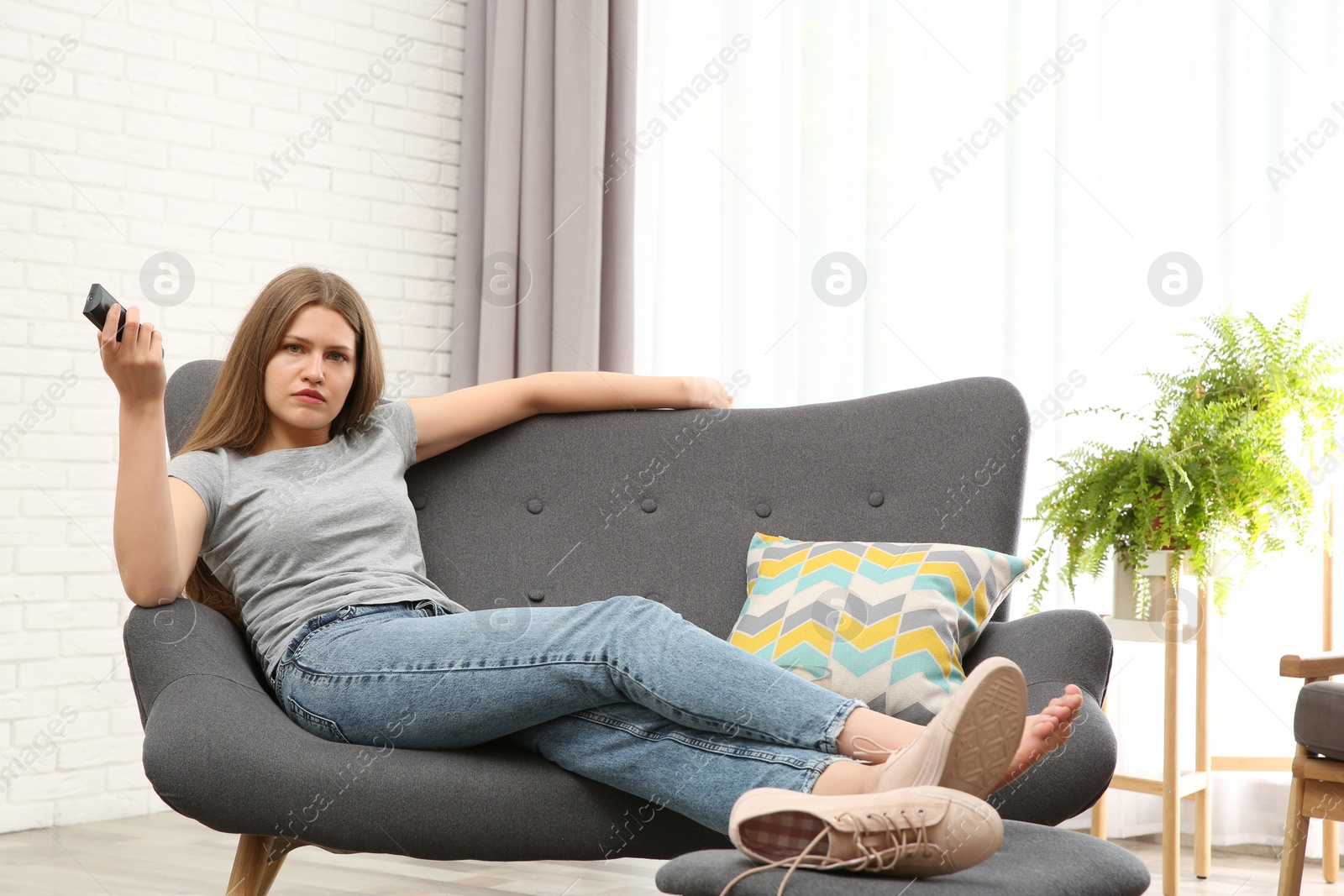 Photo of Lazy young woman watching TV at home