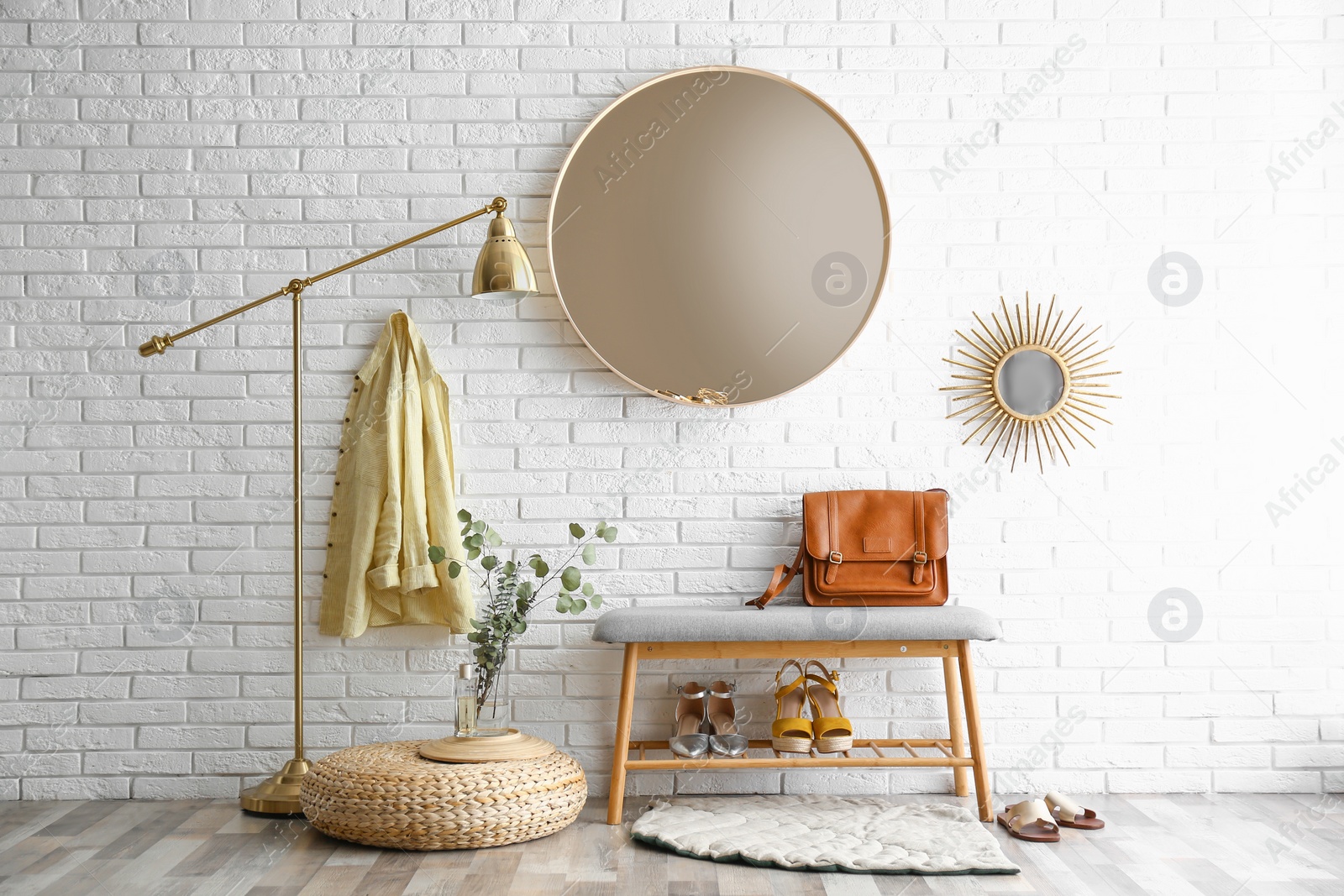 Photo of Hallway interior with big round mirror and shoe storage bench near brick wall