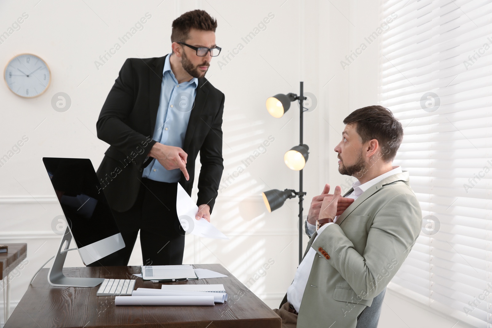 Photo of Boss scolding employee in office. Toxic work environment