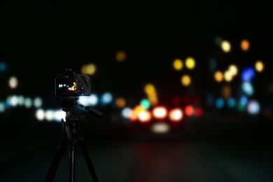 Image of Taking photo of with camera mounted on tripod. Blurred view of city lights at night, bokeh effect