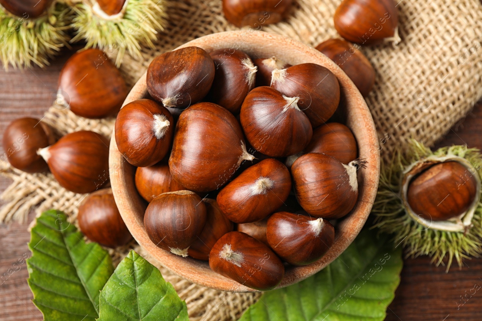 Photo of Fresh sweet edible chestnuts on brown wooden table, flat lay