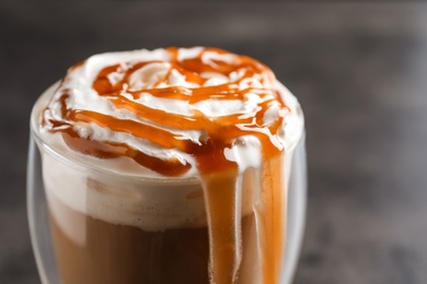 Photo of Glass with delicious caramel frappe on grey background, closeup