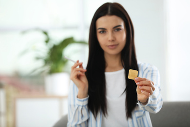 Photo of Happy young woman with nicotine patch and cigarette at home, focus on hand