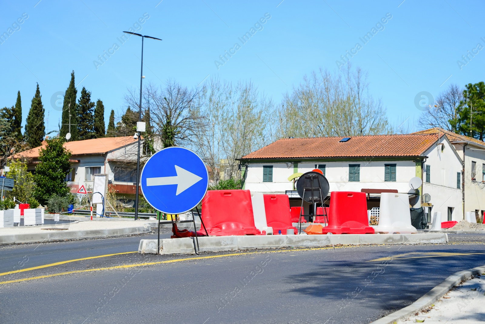 Photo of Street with road sign One Way Traffic, plastic safety barrier and temporary yellow markings on sunny day. Construction works